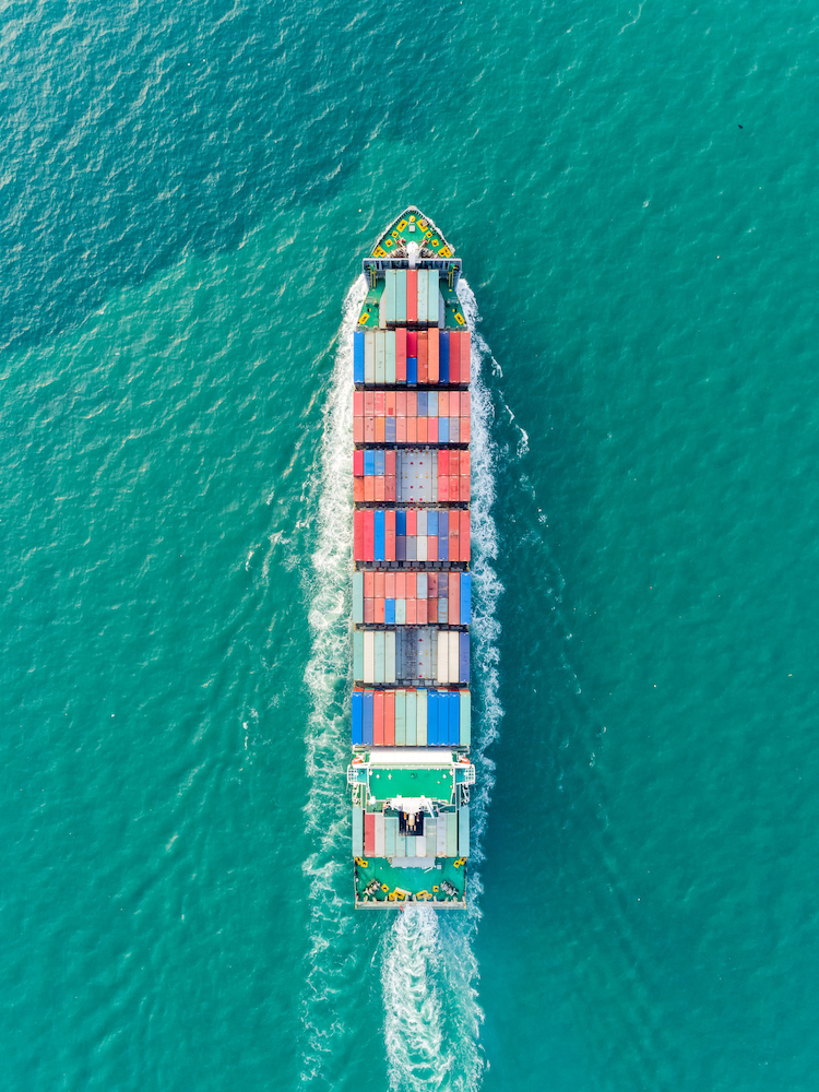 Aerial top view container ship on the seaa full speed delivering container for logistics, import export, shipping or transportation.