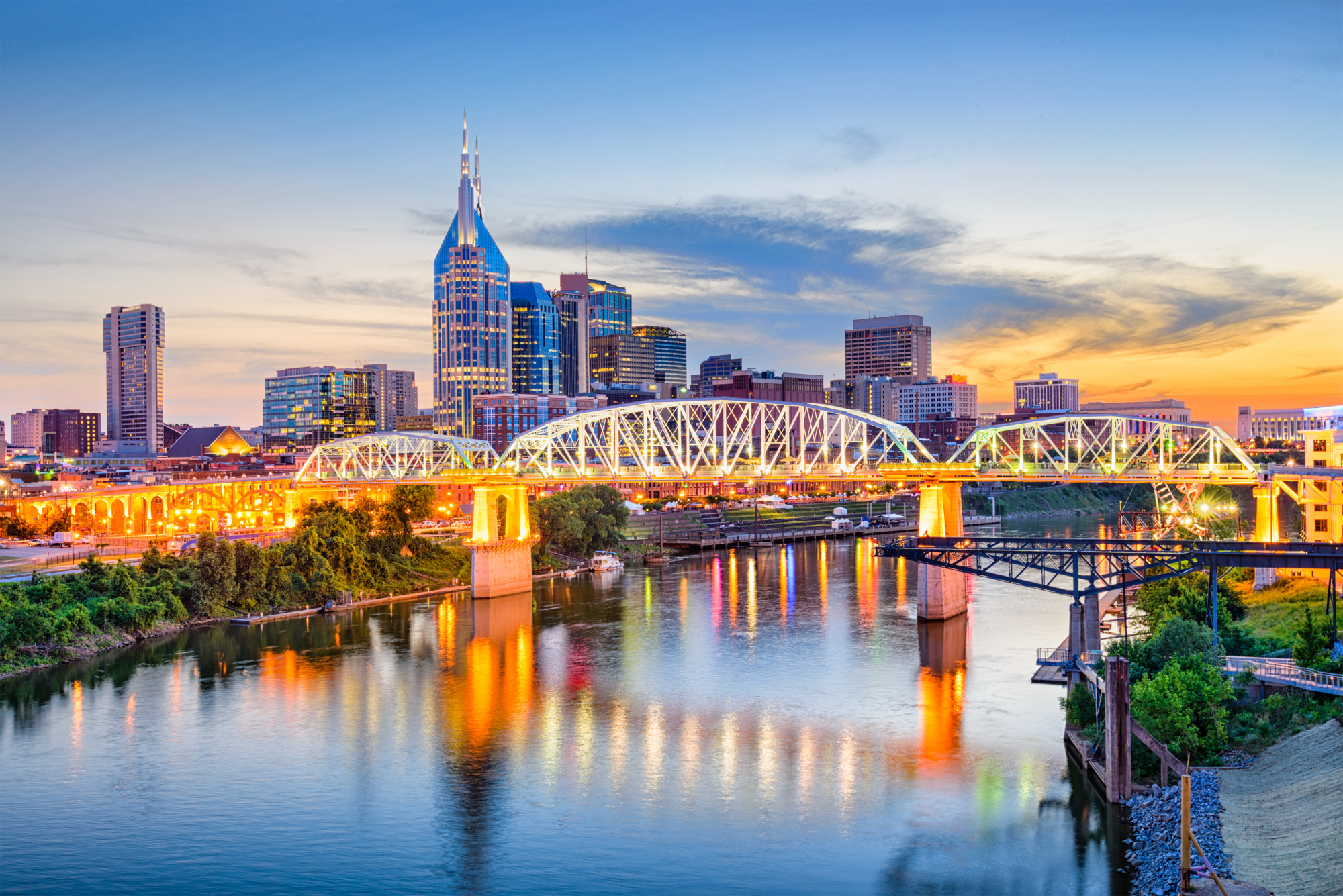 a bridge over a river with a city skyline in the background