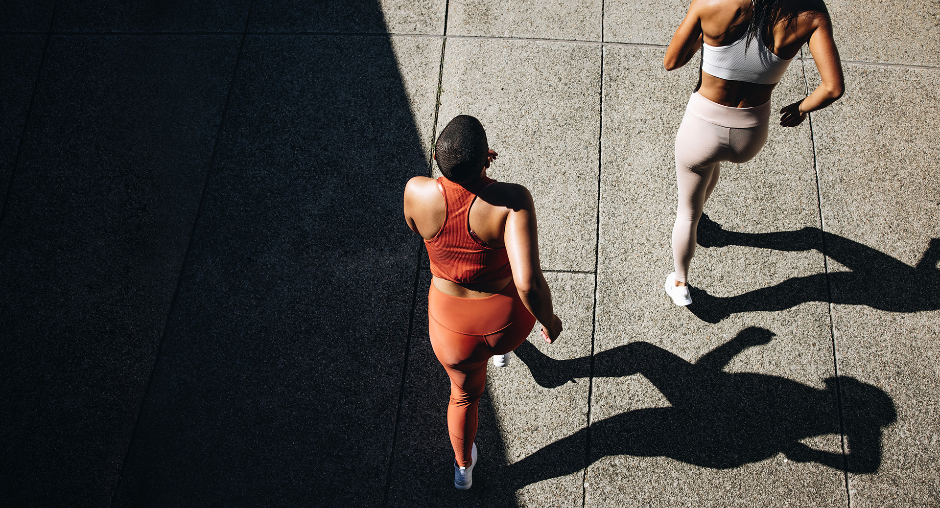 Top view of a two women in running attire jogging together. Female friends working out together in morning.