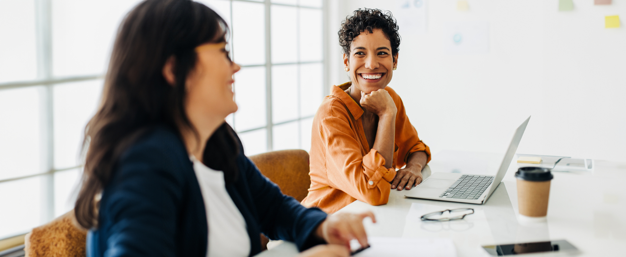 Happy business woman talking to her colleague in a boardroom. Group of business professionals having a team meeting. Creative business people planning a project in an office.