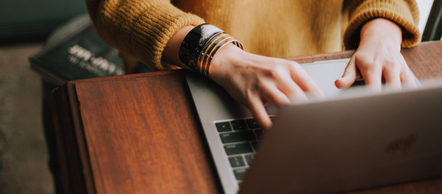 A person in yellow sweater using a laptop.