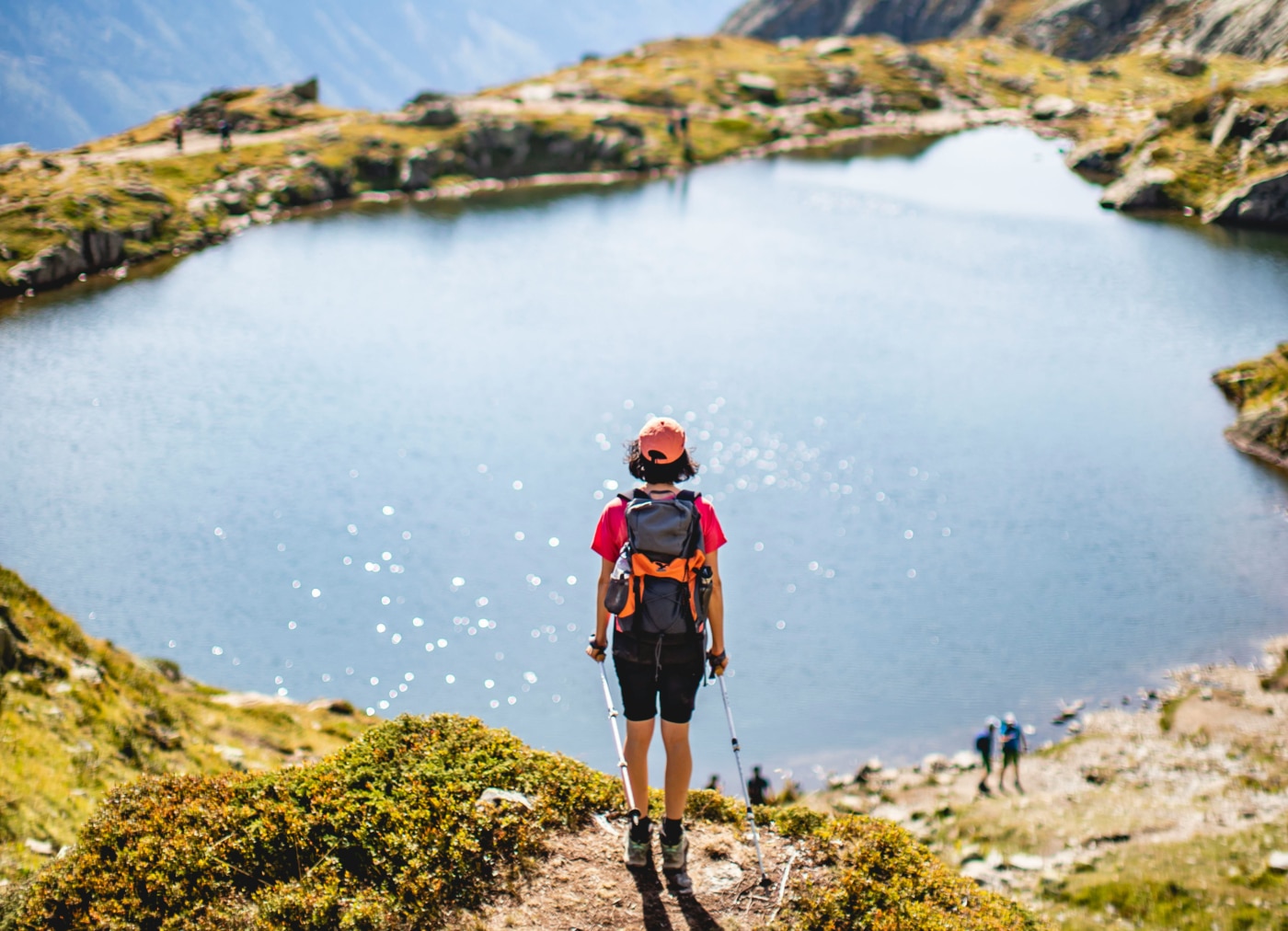 a person with a backpack stands on a hill overlooking a lake