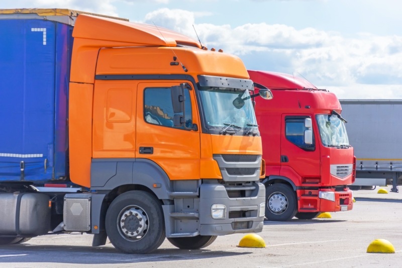 Two european trucks, orange and red.