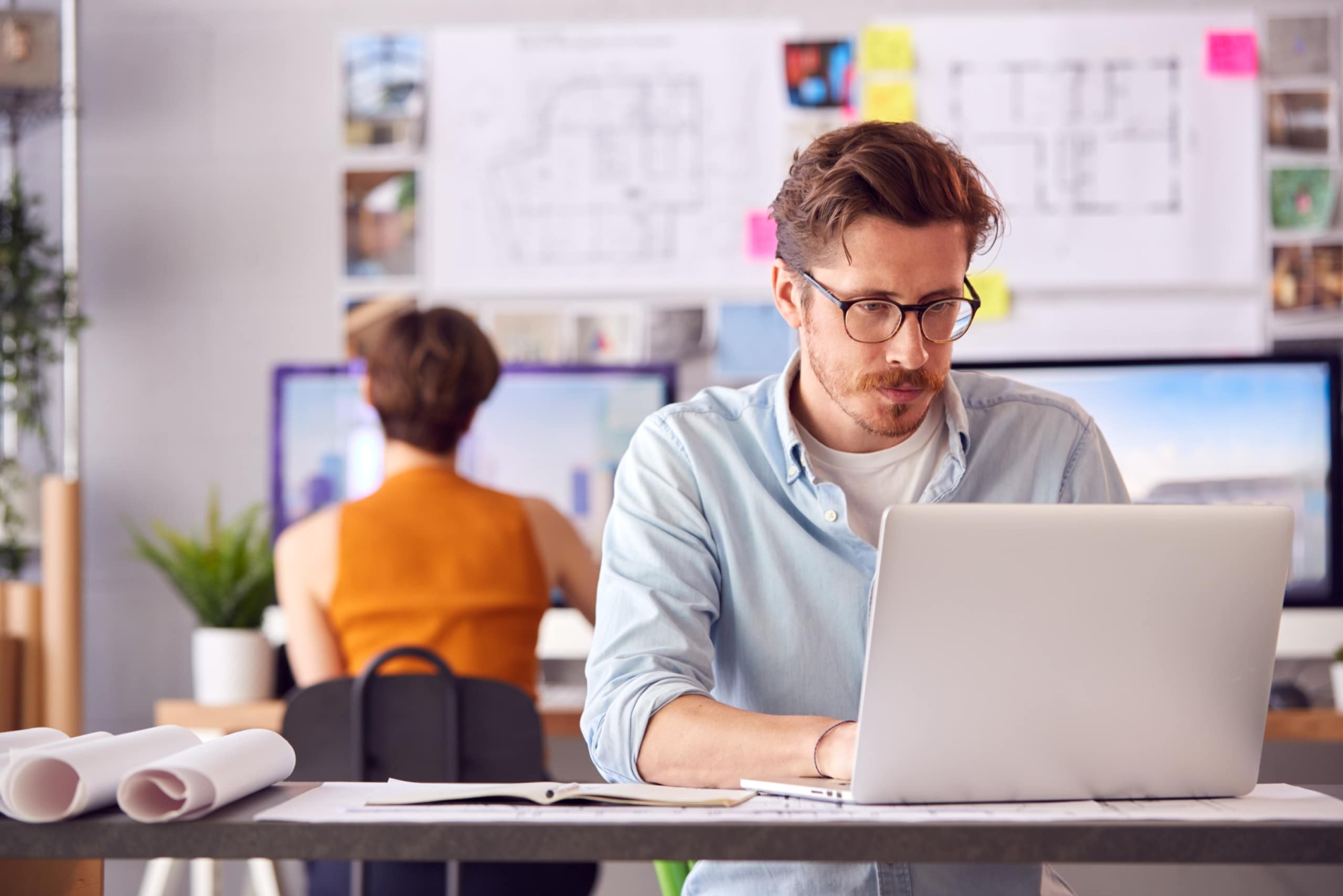 a man wearing glasses is working on a laptop computer