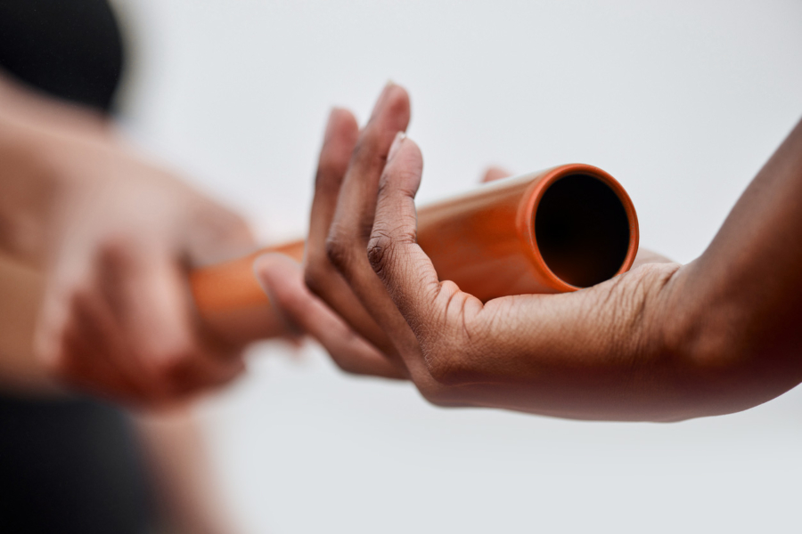 Close up photo of hands passing running baton.