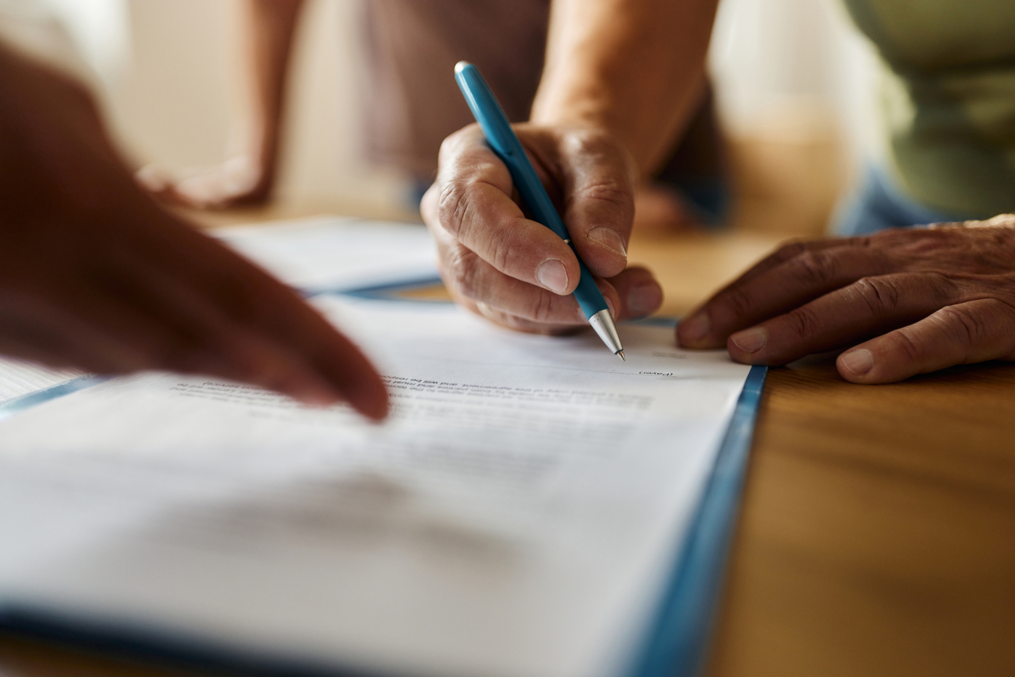 a person is signing a document with a blue pen