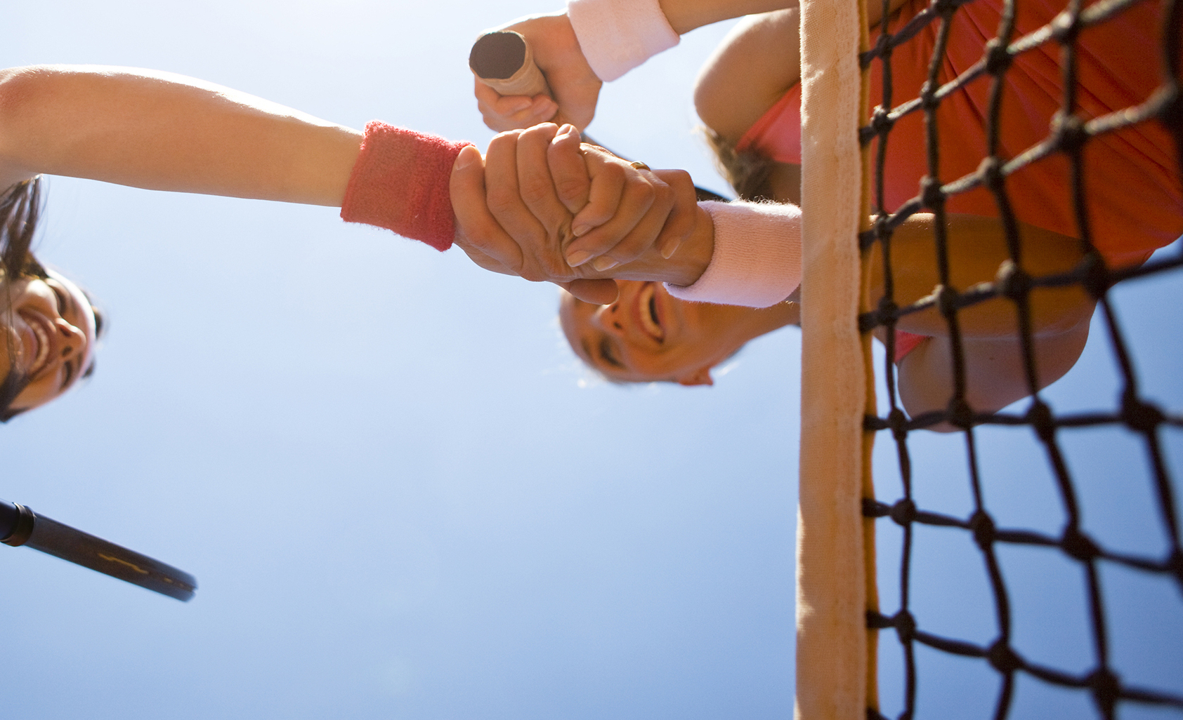 Two women shaking hands during tennis match shot from below