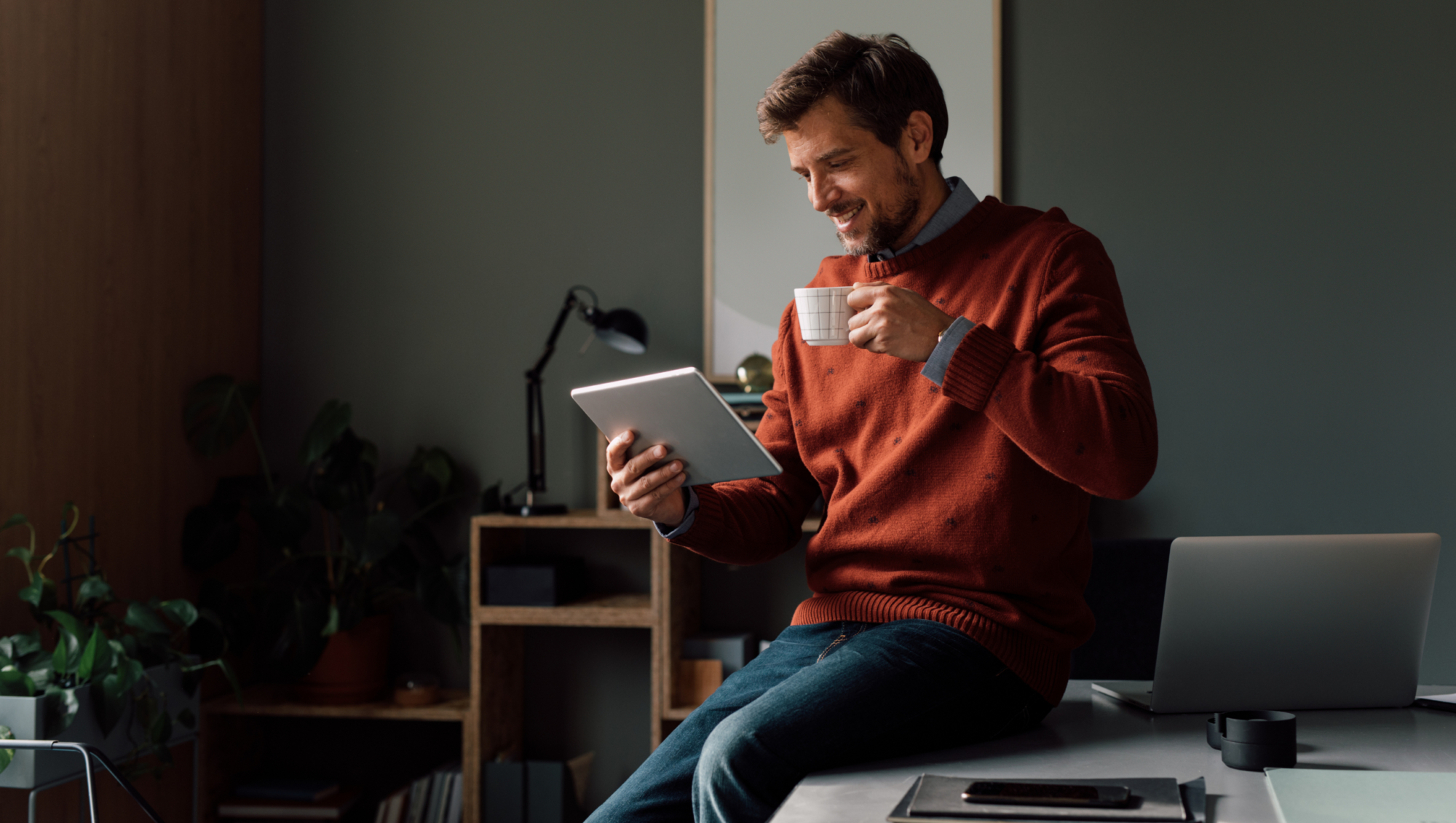 A Happy Handsome Businessman Using His Tablet While Working In The Office