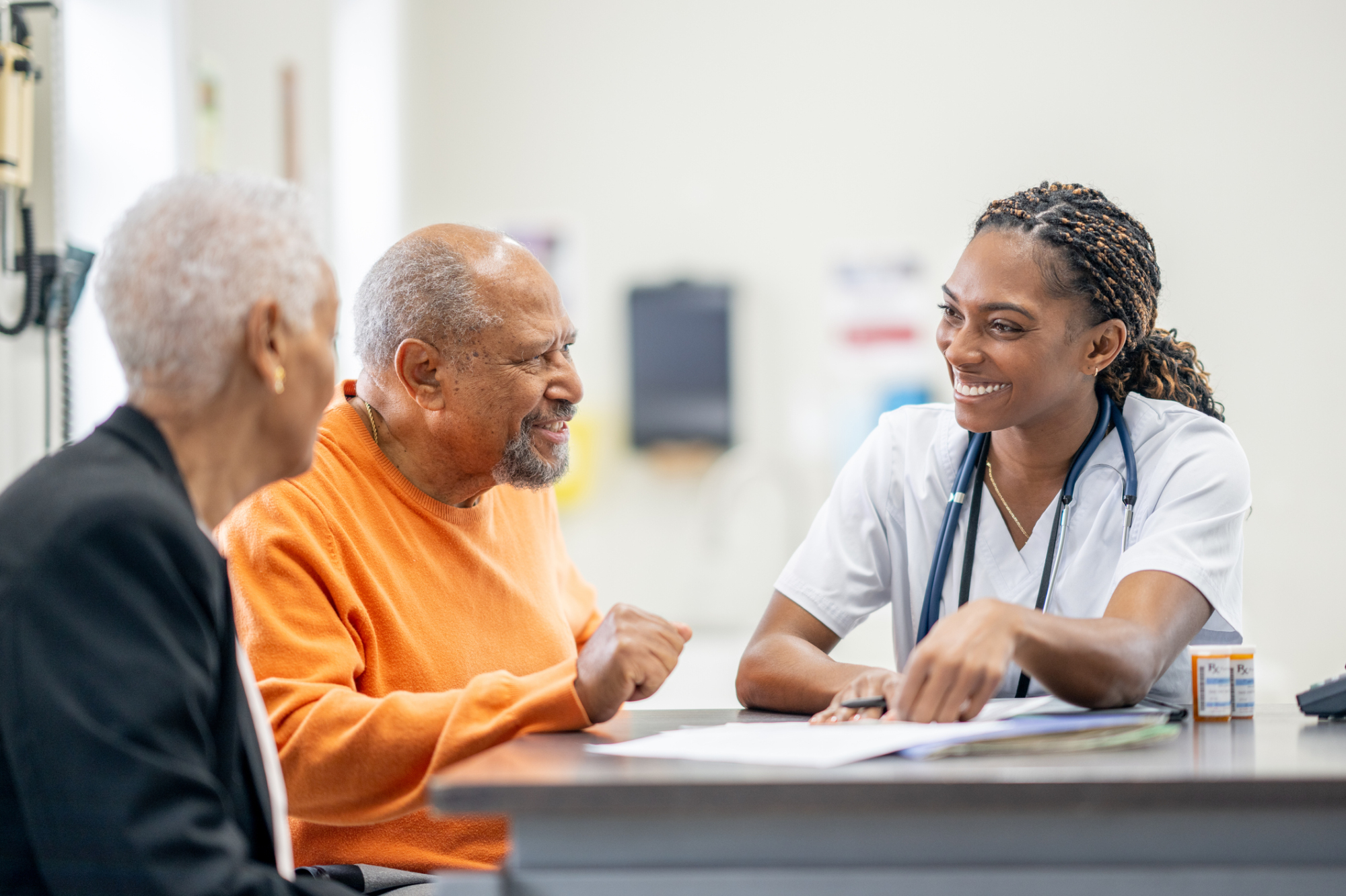 a nurse is smiling while talking to two elderly people