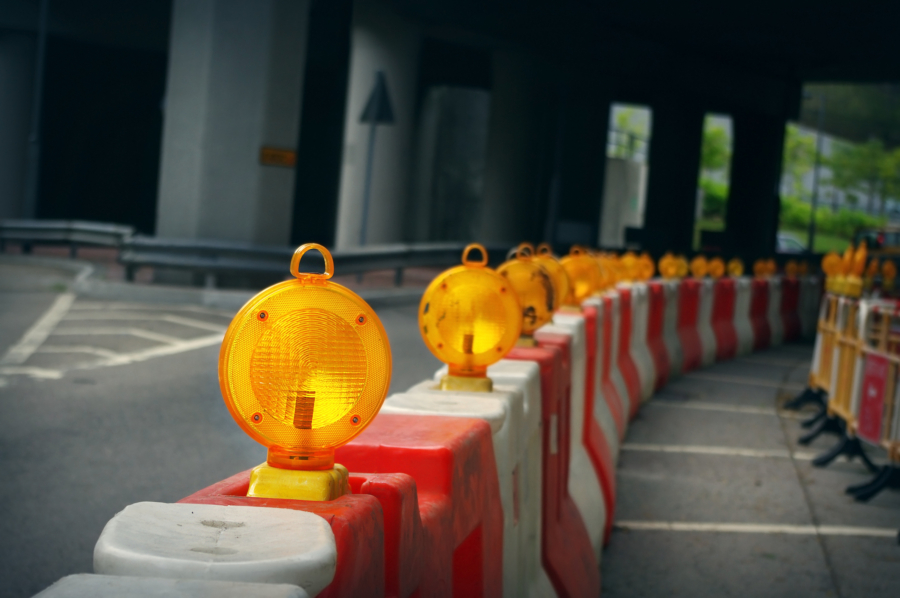 a row of orange and white barriers with a yellow light in the middle
