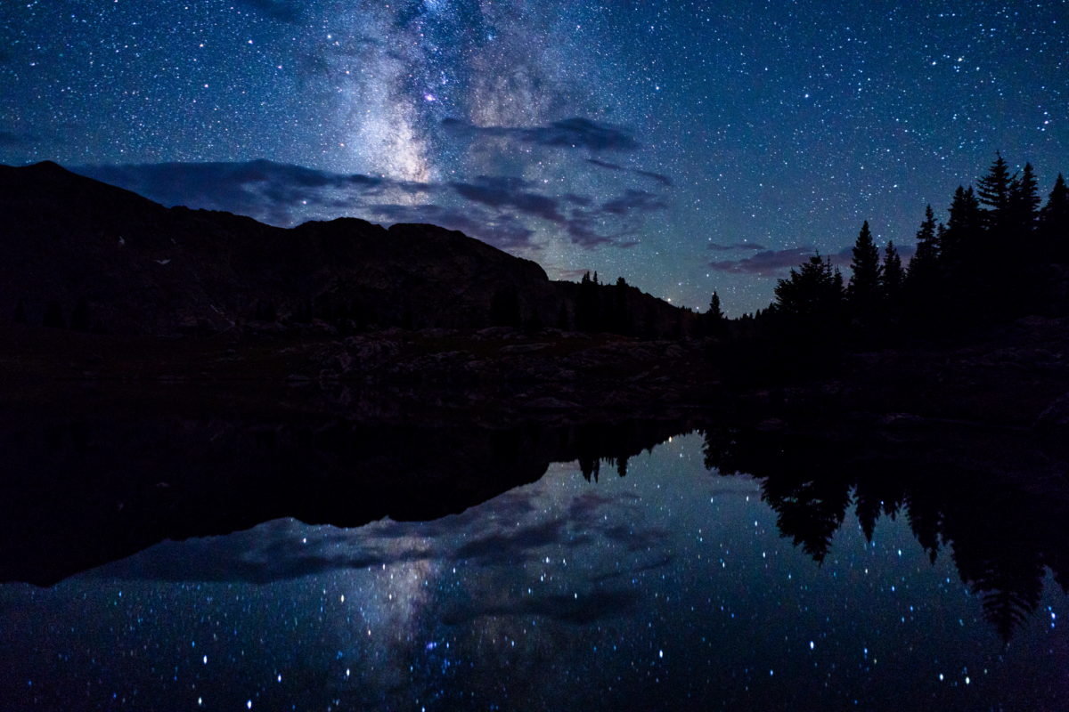 the milky way is reflected in a lake with mountains in the background