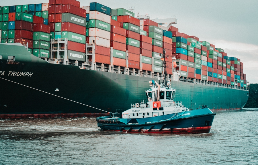 Small tugboat pulling a big container ship.