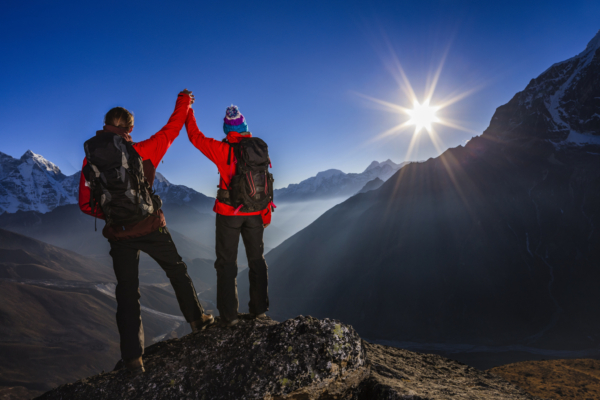 two people giving each other a high five on top of a mountain