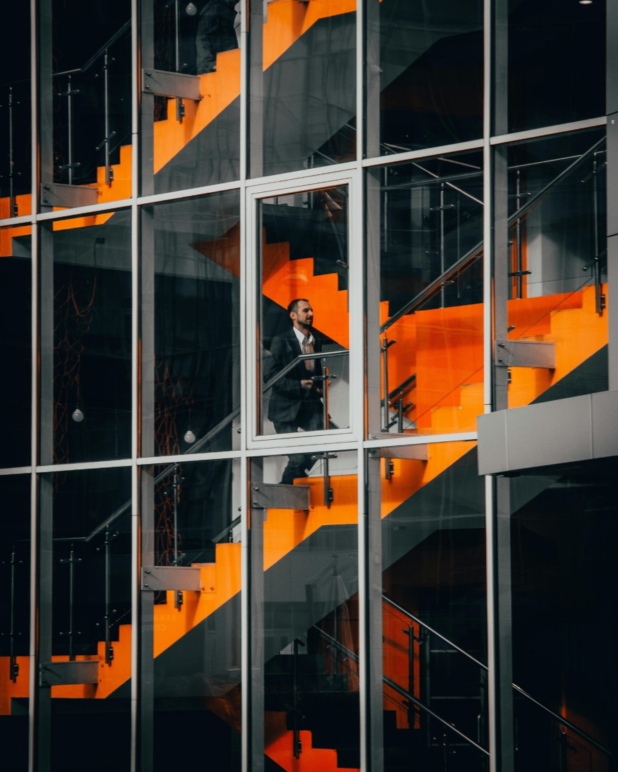 a man in a suit stands on a set of orange stairs