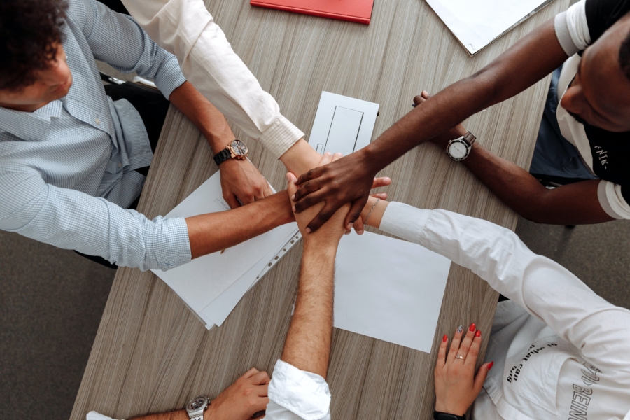 Top down view of 5 people crossing hands.