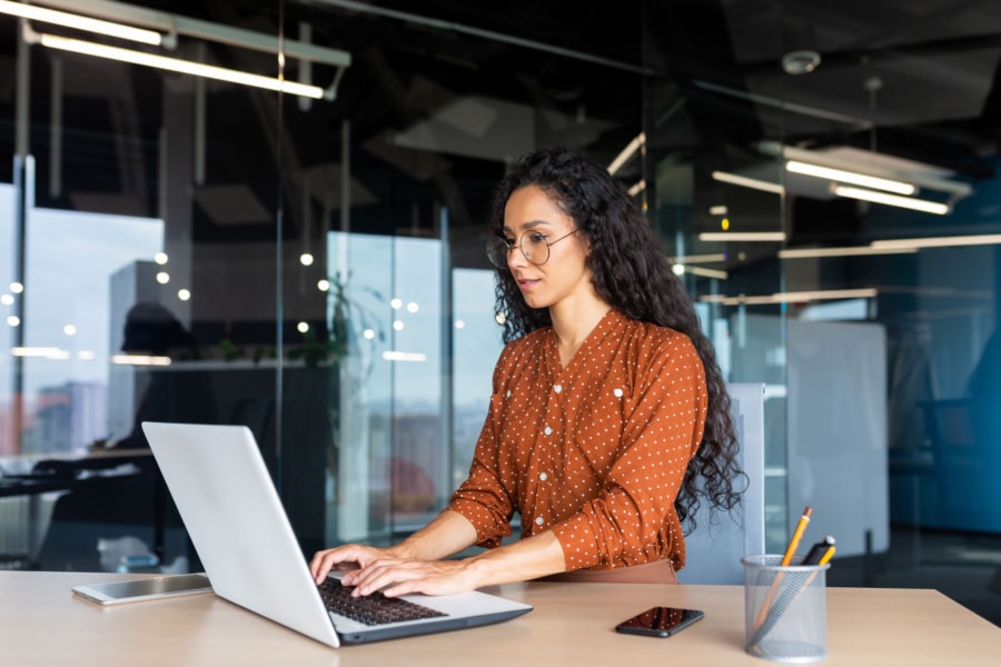 a woman wearing glasses is typing on a laptop