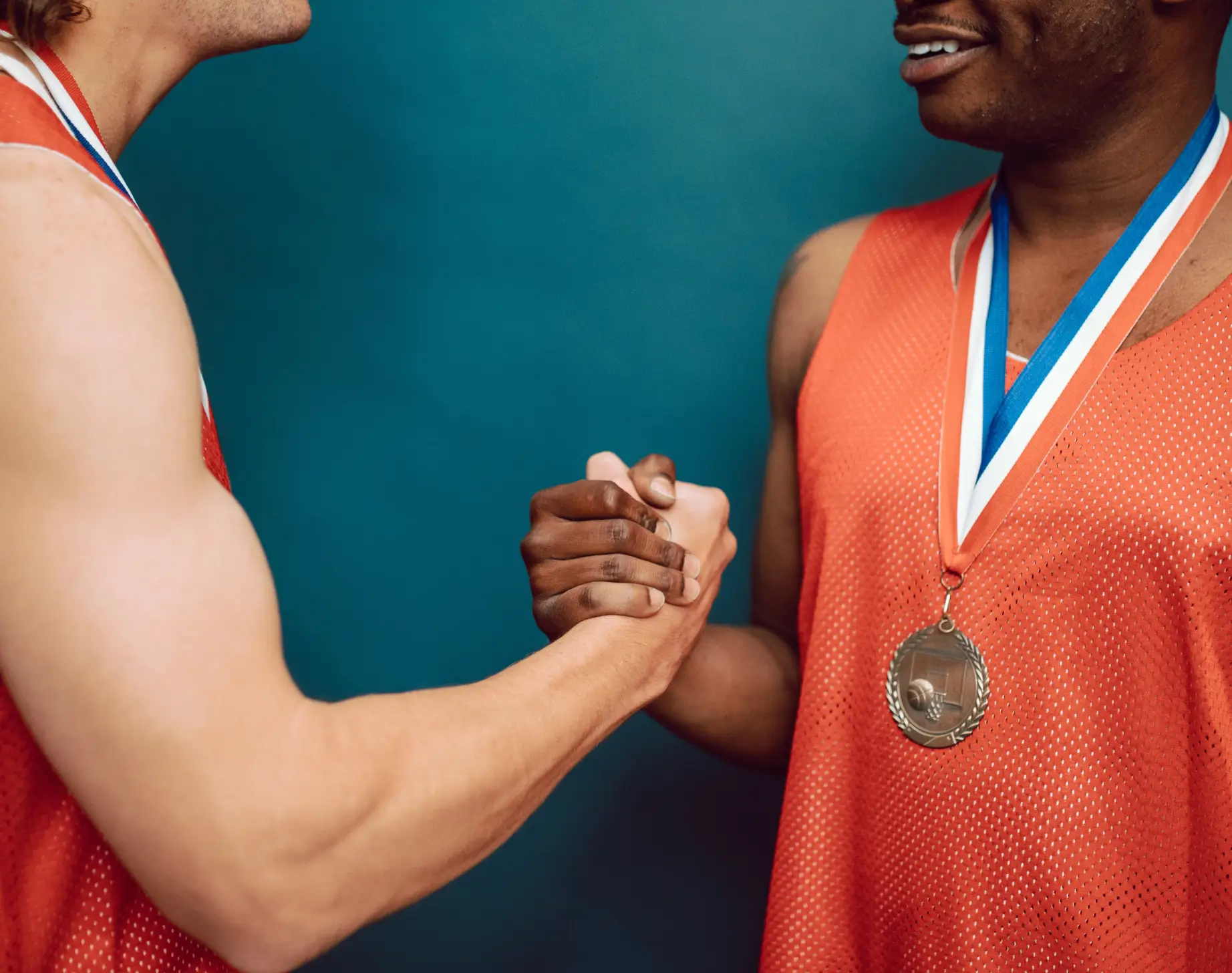 Two athletes with medals shaking hands.