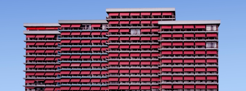 Four buildings with red balcony curtains.