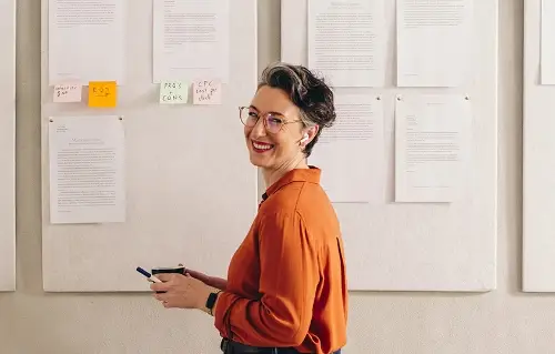 a woman is standing in front of a whiteboard with sticky notes on it .
