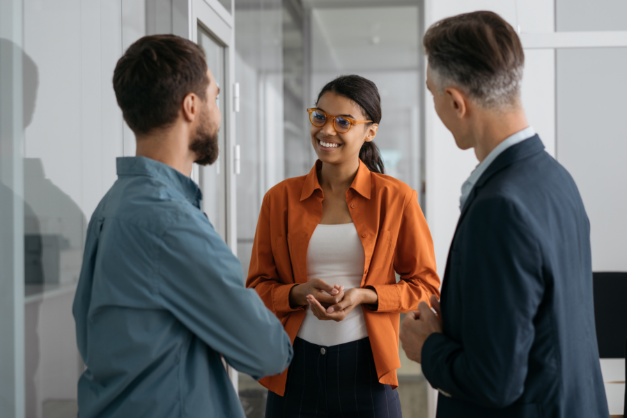 African American woman explaining something to two male white colleagues in an office